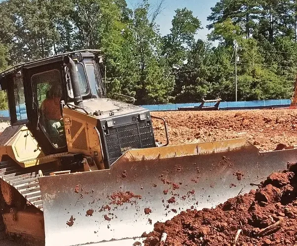 A large yellow bulldozer moving dirt and debris at a Florida construction site, clearing the land for future development
